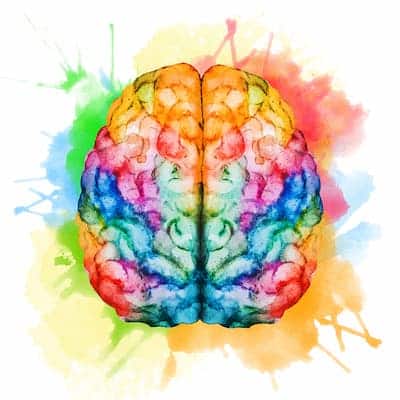 A colorful watercolor illustration of a human brain viewed from above, showcasing the left and right hemispheres. The brain is filled with a vibrant rainbow gradient of colors, surrounded by abstract splatters of green, blue, yellow, and red paint against a solid white background.